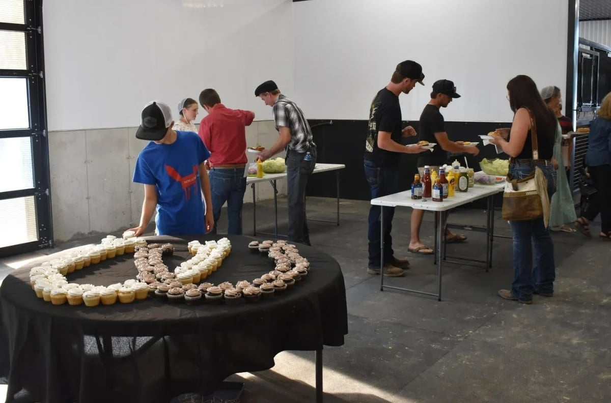 Group of people gathered in an indoor event space around a table with pastries and refreshments